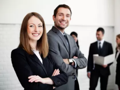 Business People im Anzug/Hosenanzug, die lächelnd in die Kamera blicken