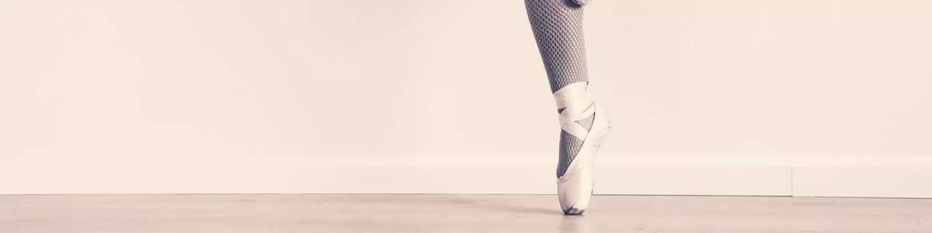 Holzboden und ein Fuß in Ballettschuhen